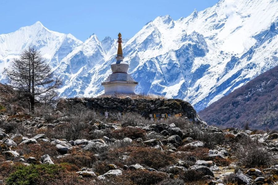 White Buddhist stupa with snow-covered Langtang Lirung mountain range in background during autumn trekking season